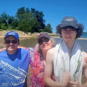 Shared Living Living Resident poses for photo at beach with his Shared Living family.